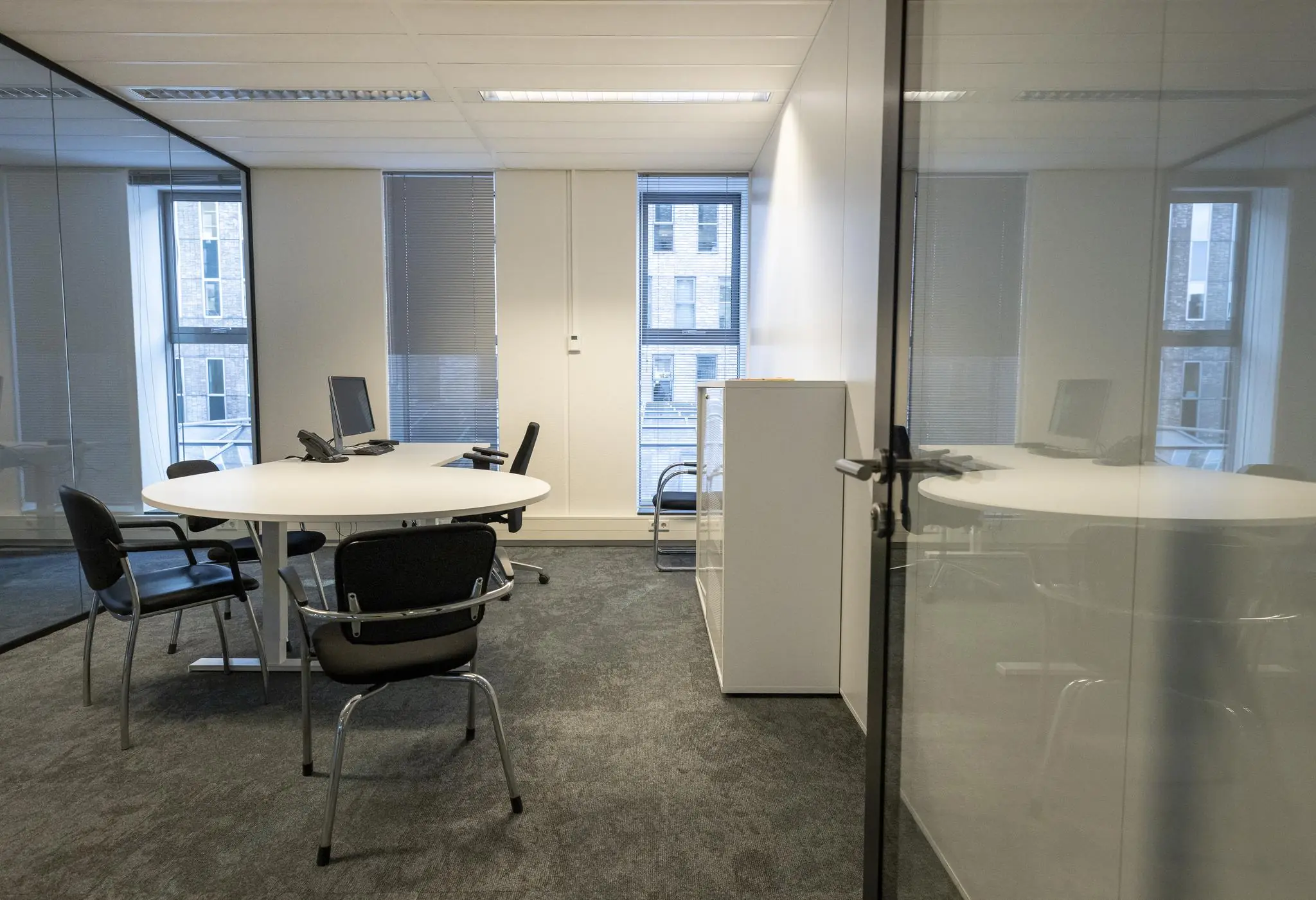 Moderne vergaderruimte aan de Prinses Beatrixlaan met ronde tafel, bureaustoelen en computerapparatuur.